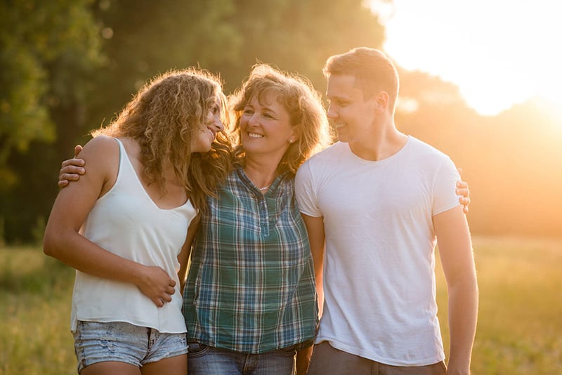 Mom walks with her teenage son and daughter on either side of her