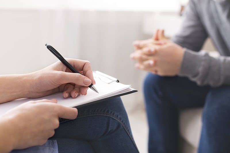 Counselor takes notes while listening to a patient