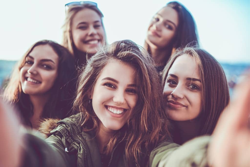 Group of teen girls smile for a photo outside