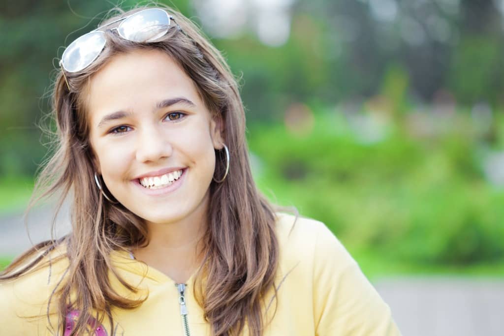 Teen girl smiles for a photo while outside