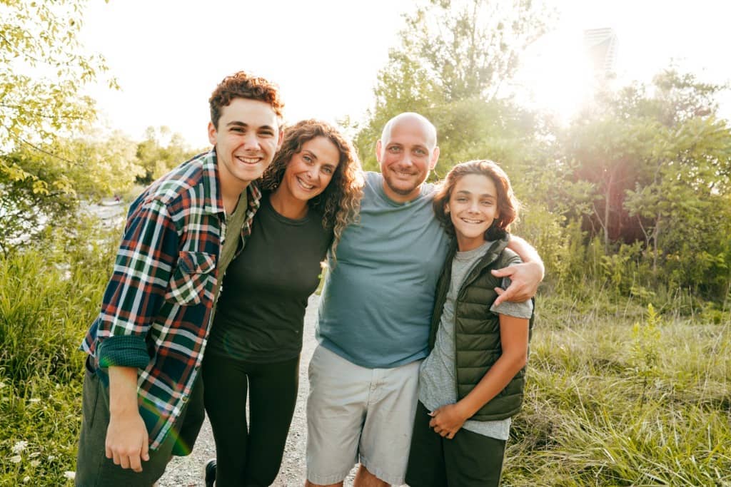 Parents pose with their two teens outside