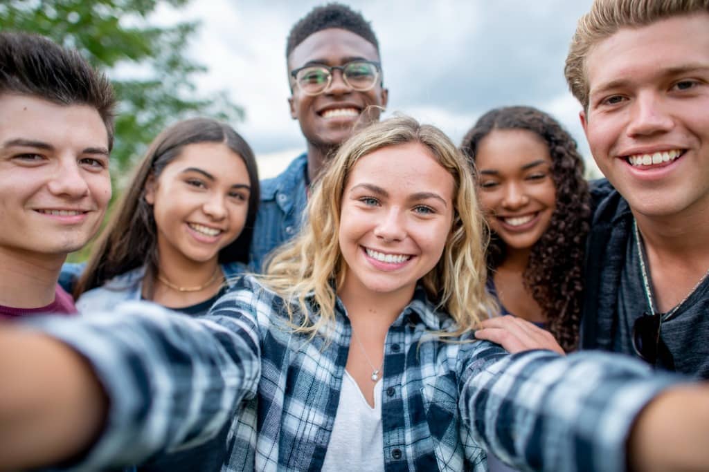 Group of teens smile for a group photo while outside