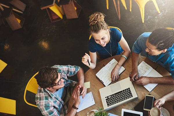 Group of young adults working at a table as a team